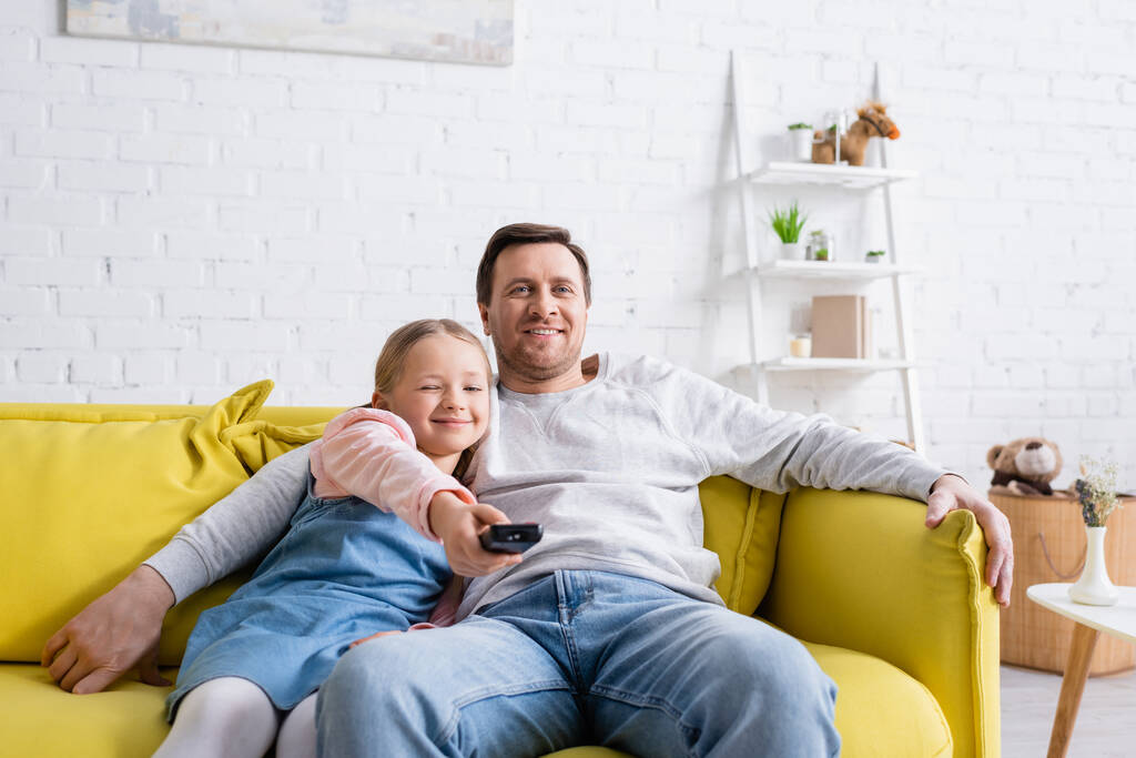 šťastný muž sledování televize s dcerou kliknutí kanály na dálkovém ovladači - Fotografie, Obrázek