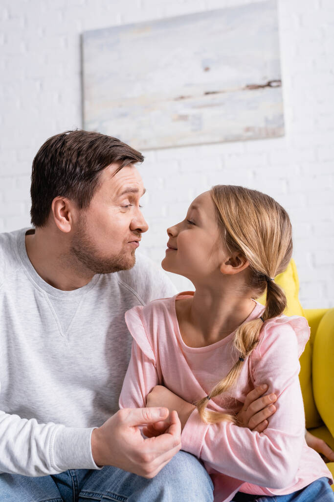 playful father and daughter grimacing at each other while having fun at home - Photo, Image