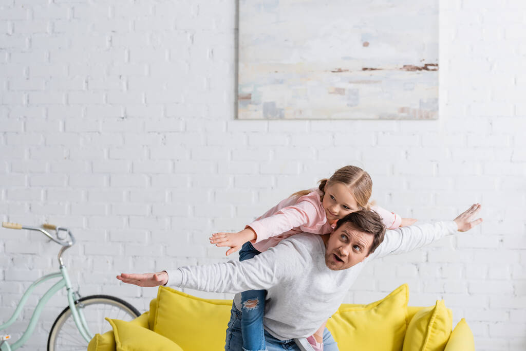отец и дочь показывают жест мухи, веселясь дома - Фото, изображение