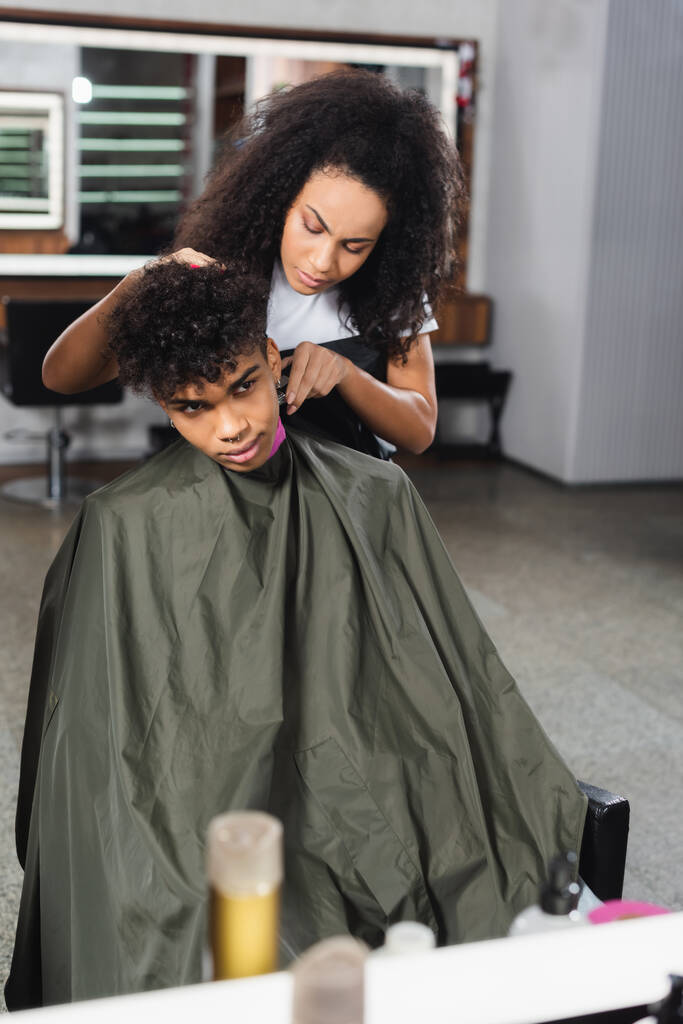 Африканский американский парикмахер стрижет шею клиенту в мысе в салоне  - Фото, изображение