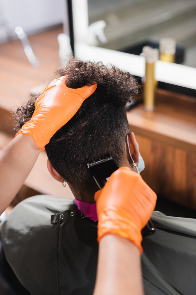 アフリカ系アメリカ人のクライアントの頭の後ろにトリミングラテックス手袋の美容師  - 写真・画像