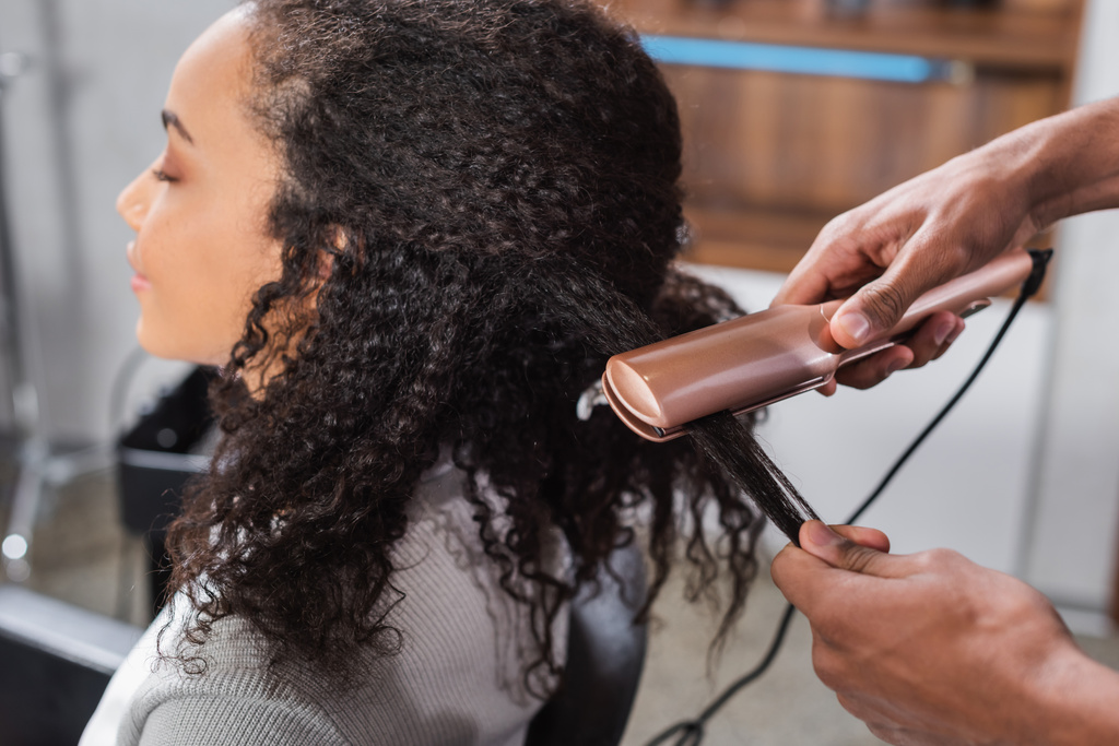 Afrikai amerikai fodrász segítségével hajvasaló az ügyfél  - Fotó, kép