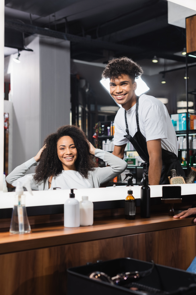 Uśmiechnięty afrykański fryzjer i klient patrzący w lustro w salonie  - Zdjęcie, obraz