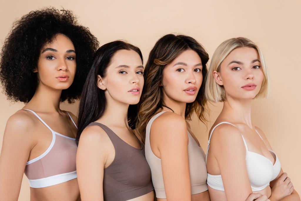 young interracial women in bras looking at camera isolated on beige - Photo, Image