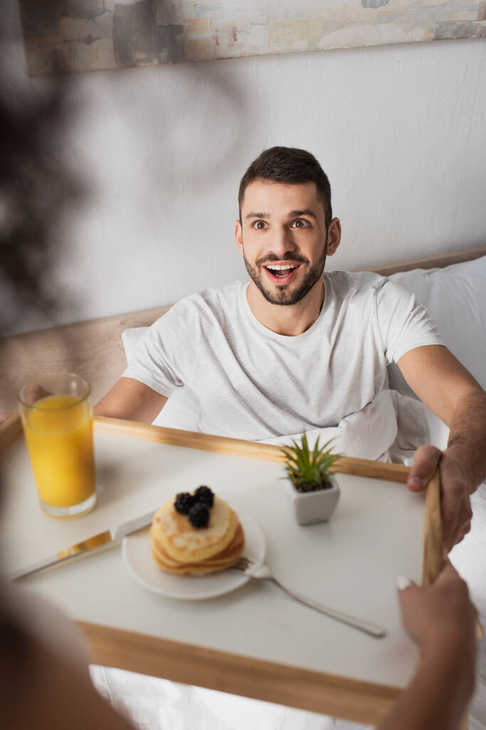 homem surpreso tomando bandeja com café da manhã de mãos de namorada americana africana  - Foto, Imagem