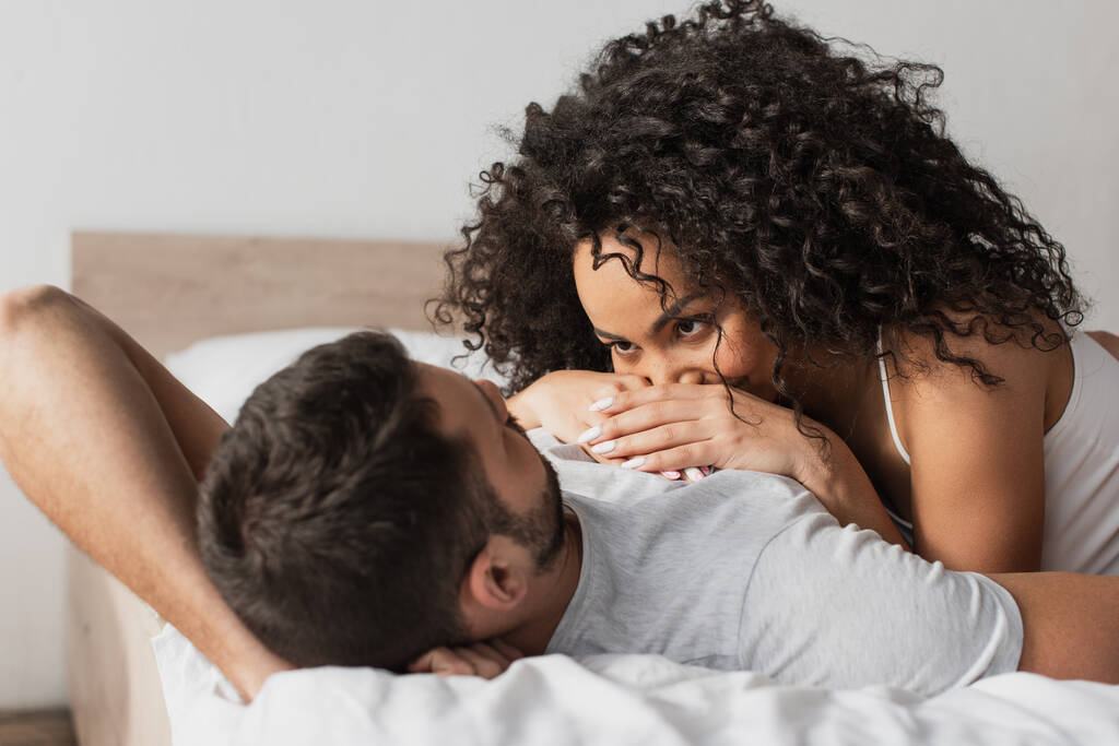 couple interracial couché ensemble sur le lit à la maison - Photo, image