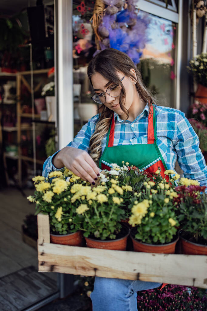 Jonge volwassen vrouw werkzaam in de stad straat bloemenwinkel of bloemist. Concept voor kleine ondernemingen. - Foto, afbeelding