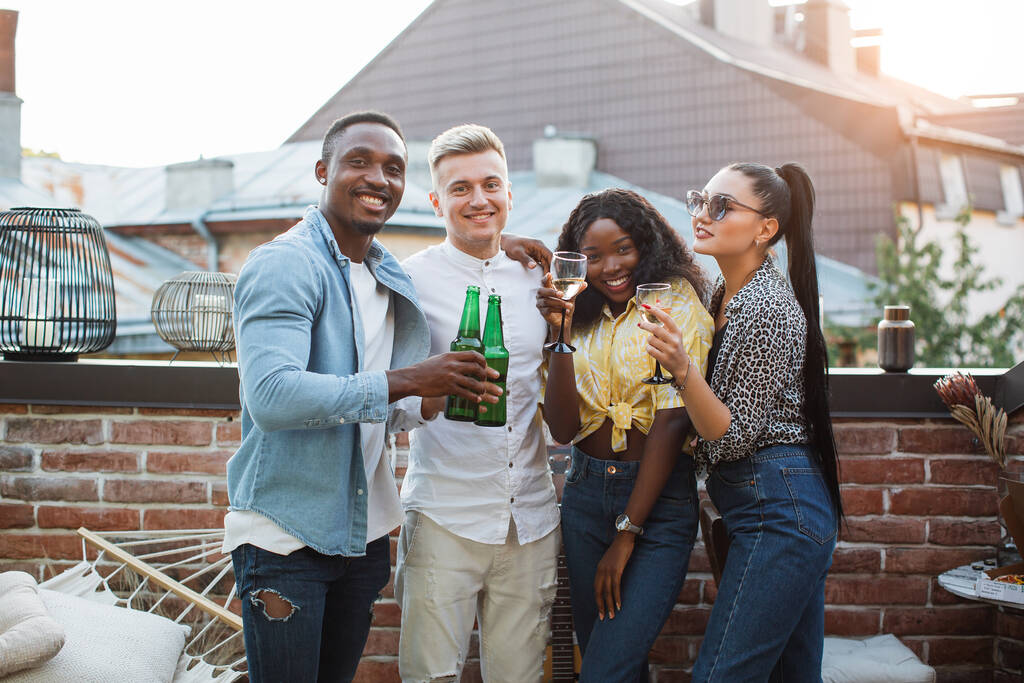Amici di razza mista godendo di bevande alcoliche sul tetto - Foto, immagini