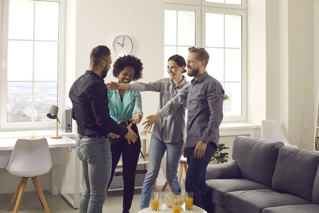 Group of happy young diverse people welcoming their friend at a cozy gathering at home - Photo, Image