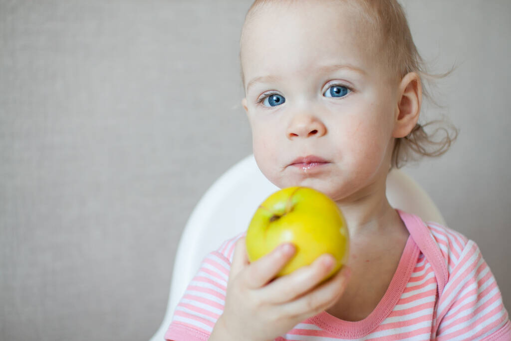 女の子は味、審査し、喜びと関心を持って新鮮なリンゴと遊ぶ. - 写真・画像