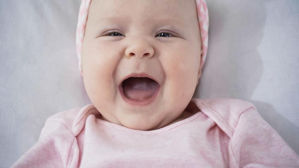 vista superior del bebé sorprendido riendo en la cama - Foto, Imagen