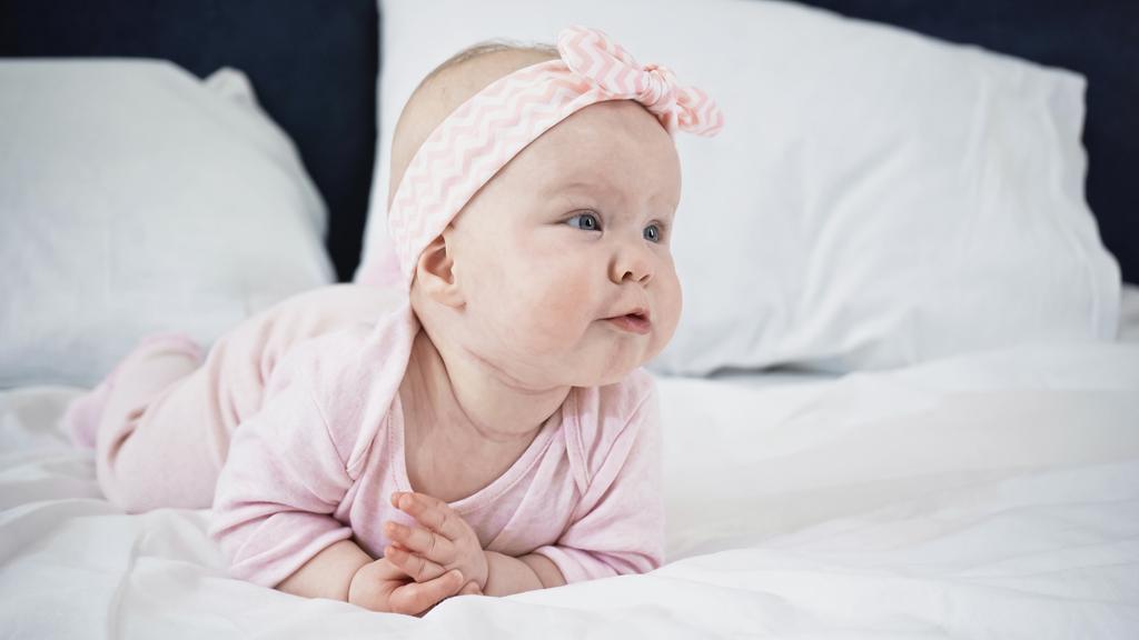 niemowlę dziewczynka leżące na łóżku podczas odwracania wzroku - Zdjęcie, obraz