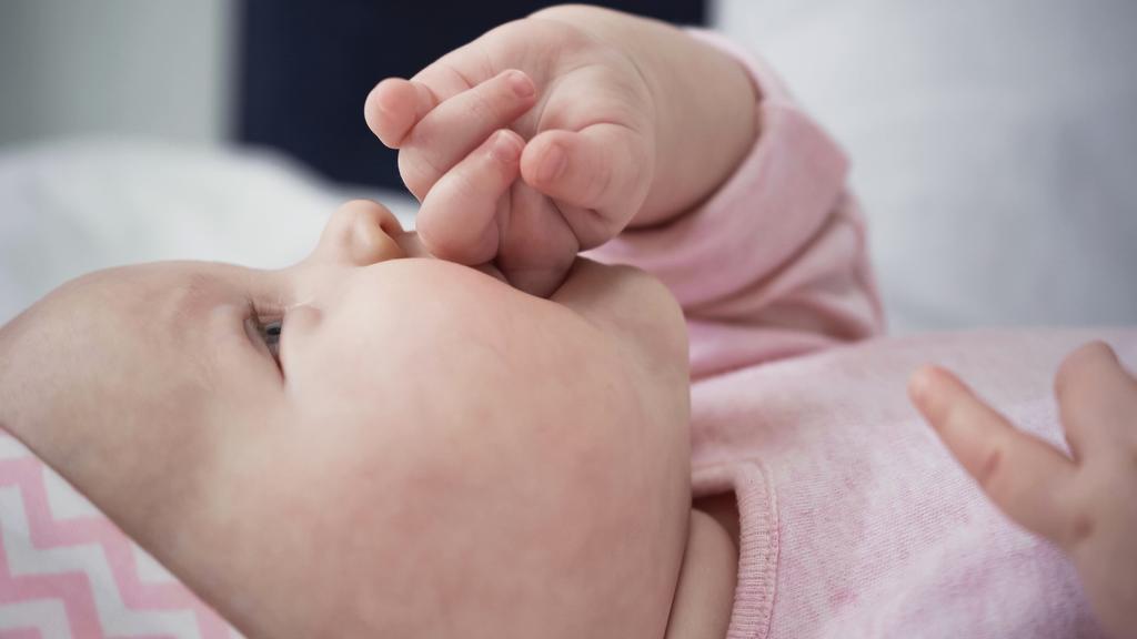 赤ちゃんの女の子が指を吸っているのを  - 写真・画像