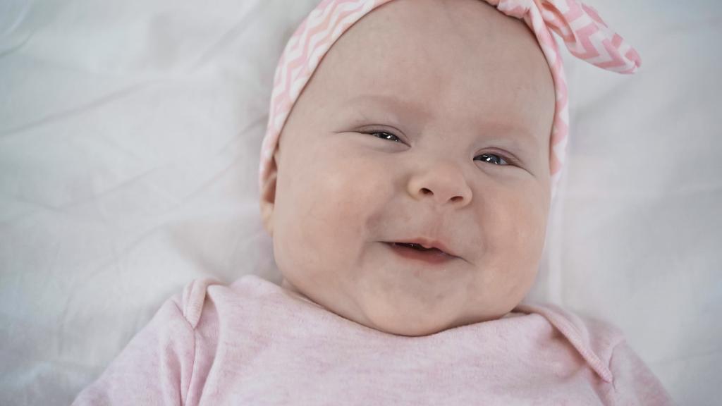 ylhäältä katsottuna iloinen vauva hymyilee katsoessaan kameraa sängyssä - Valokuva, kuva