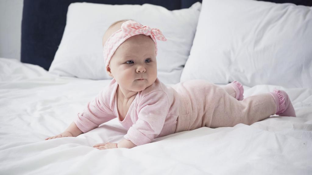 bebê menina na cabeça com arco deitado na cama - Foto, Imagem