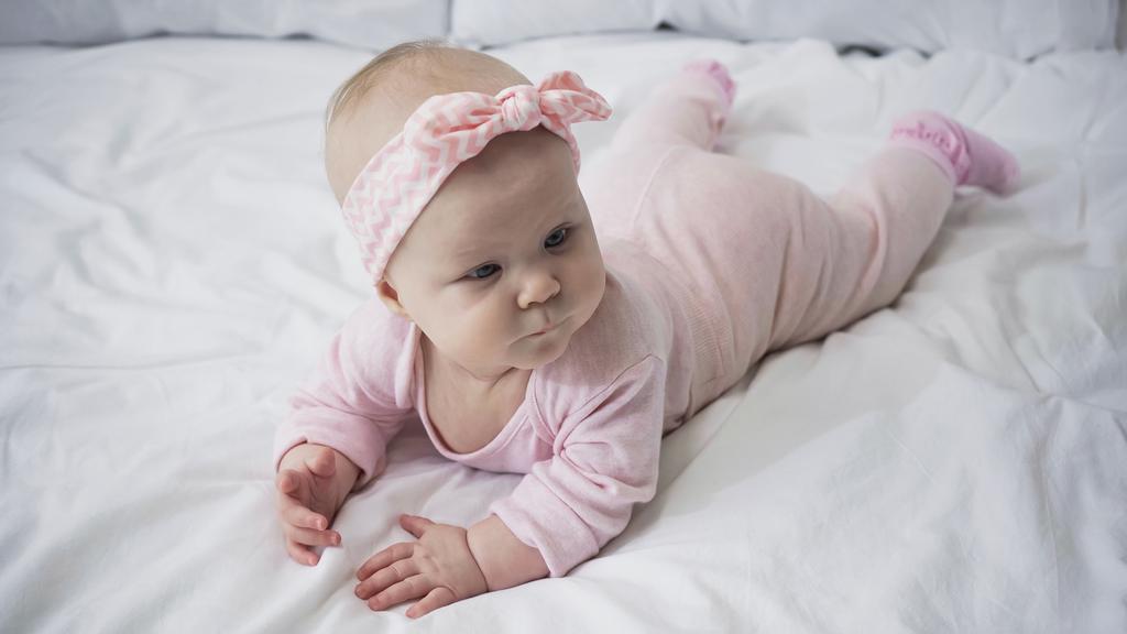  bambina in fascia con fiocco sdraiata sul letto - Foto, immagini