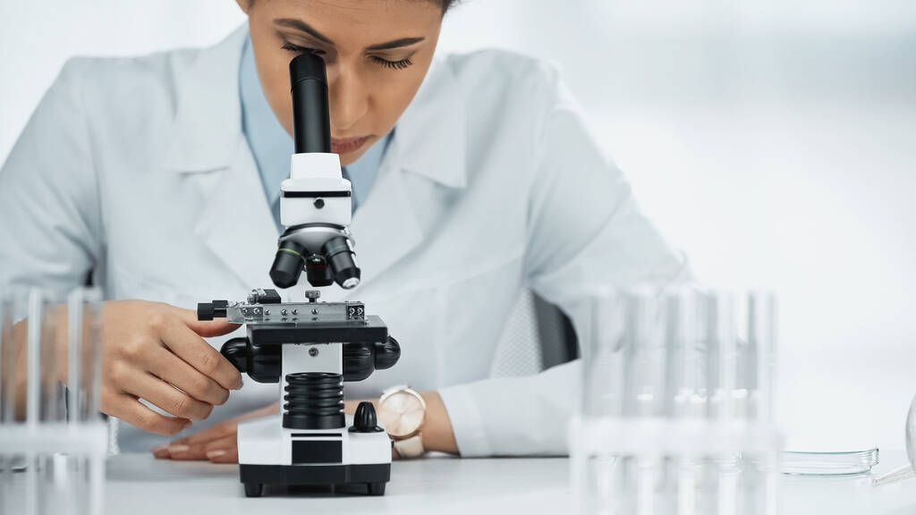 scientifique afro-américain dans les lunettes regardant à travers le microscope en laboratoire  - Photo, image
