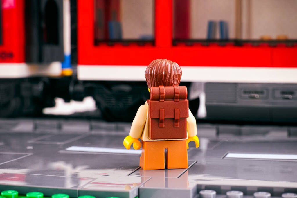 Tambov, Ruská federace - 03. 3. 2021 Lego turista s batohem stojící zády ke kameře na nástupišti před červeným vlakem - Fotografie, Obrázek