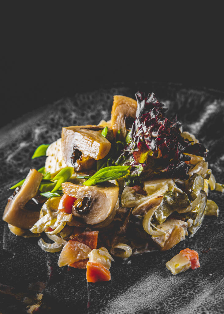 Геркінс, гриби, цибуля та сирний салат у тарілці на фоні чорного дерев'яного столу
 - Фото, зображення