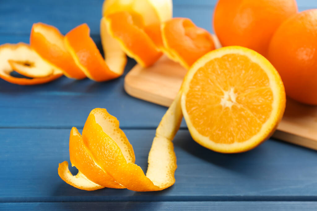 Апельсиновые фрукты с кожурой на голубом деревянном столе - Фото, изображение