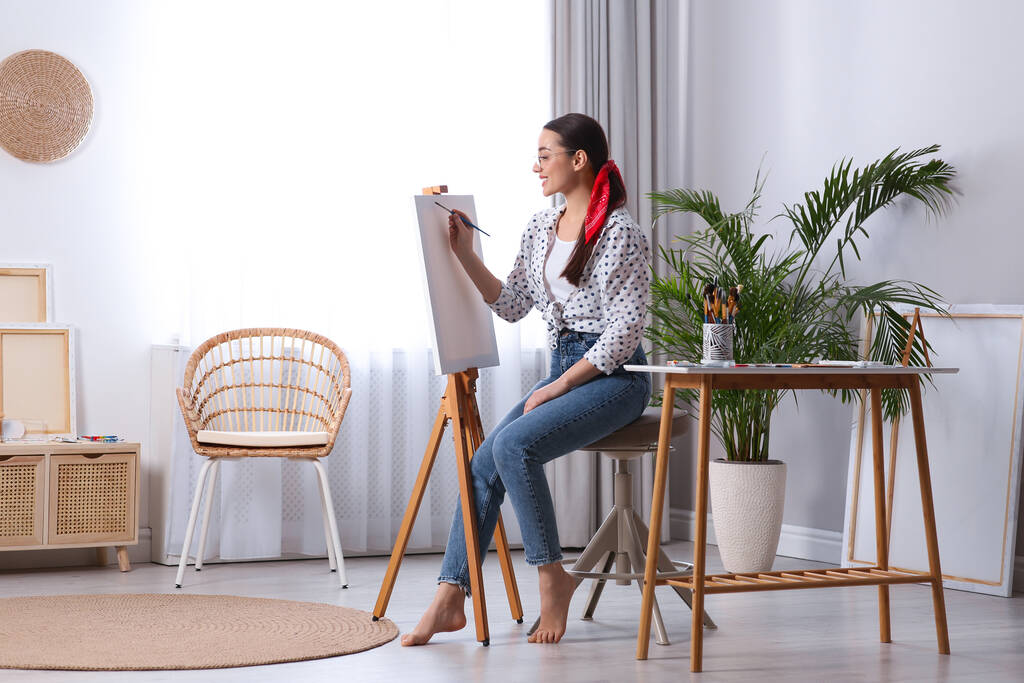 Happy woman artist drawing picture on canvas in studio - Photo, Image
