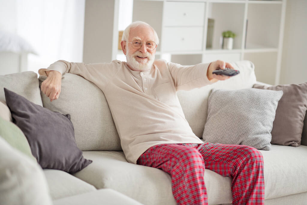 Fénykép az idős férfi boldog pozitív mosoly ül kanapé ház szórakozás nézni televízió kapcsoló csatorna távirányító - Fotó, kép