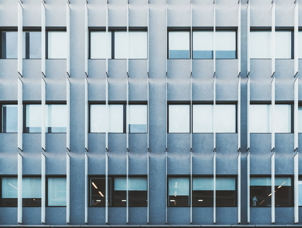 Vista di una moderna facciata del grattacielo aziendale con pannelli fonoassorbenti verticali sospesi; una texture di un grattacielo ufficio blu con finestre e barre insonorizzanti come parte della costruzione - Foto, immagini