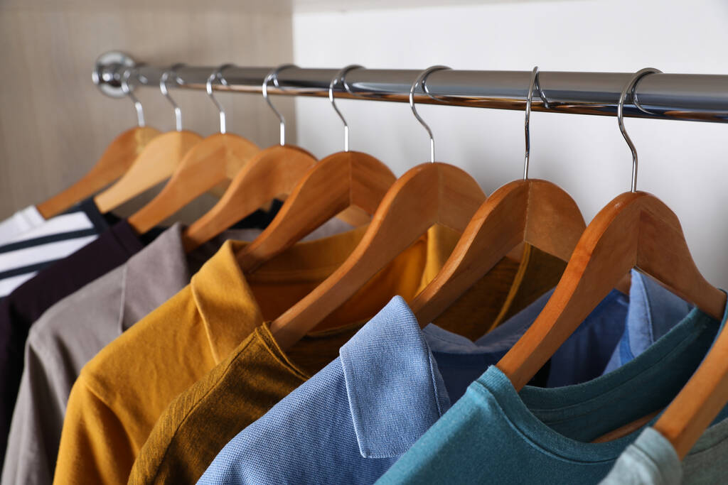 Différents vêtements élégants suspendus sur le rack dans la garde-robe, gros plan - Photo, image
