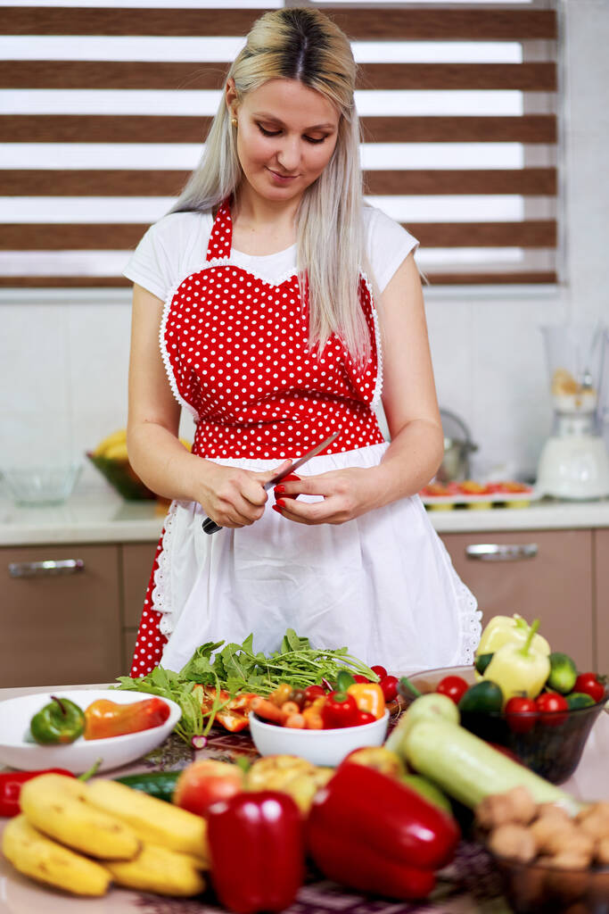 Nuori nainen keittiössä kasan vihanneksia ja hedelmiä - Valokuva, kuva