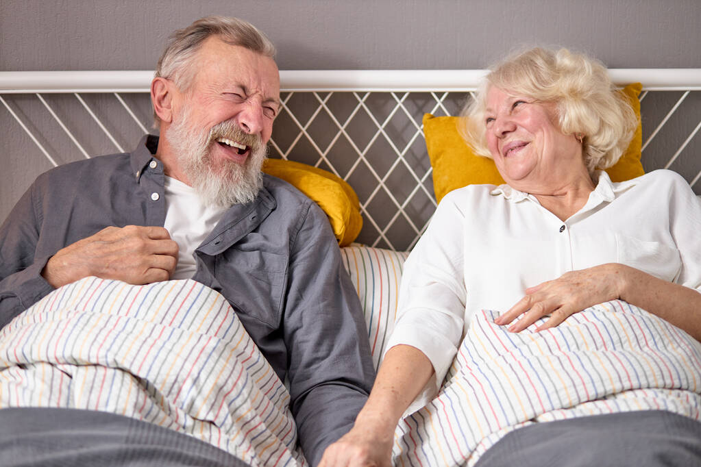 Le couple âgé caucasien positif s'amuse. rire en étant couché sur le lit à la maison - Photo, image