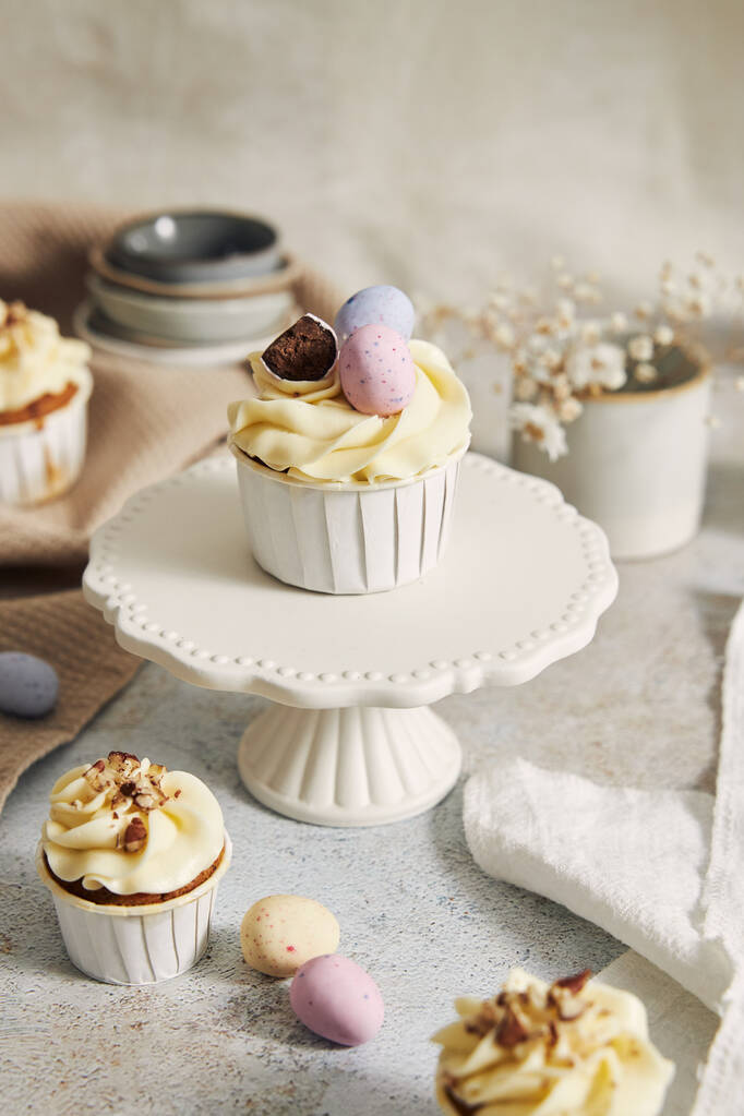 Un plano vertical de pequeños cupcakes con crema blanca y caramelos - Foto, Imagen