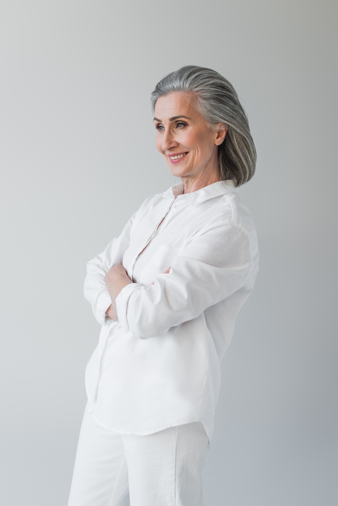Middle aged woman smiling with crossed arms isolated on grey  - Photo, Image