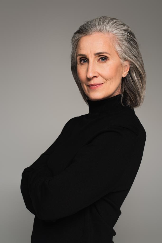 Portret van volwassen vrouw in zwart coltrui geïsoleerd op grijs  - Foto, afbeelding