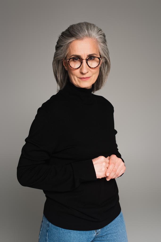 Retrato de mujer madura en anteojos y cuello alto aislado en gris  - Foto, Imagen