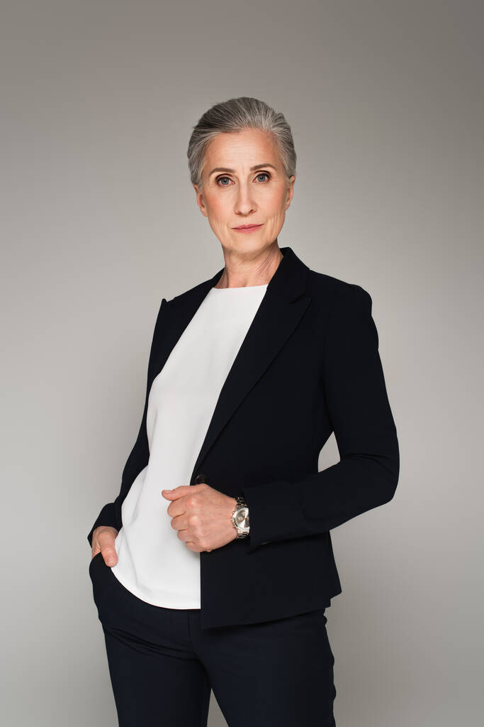 Mature businesswoman in formal wear looking at camera isolated on grey  - Photo, Image