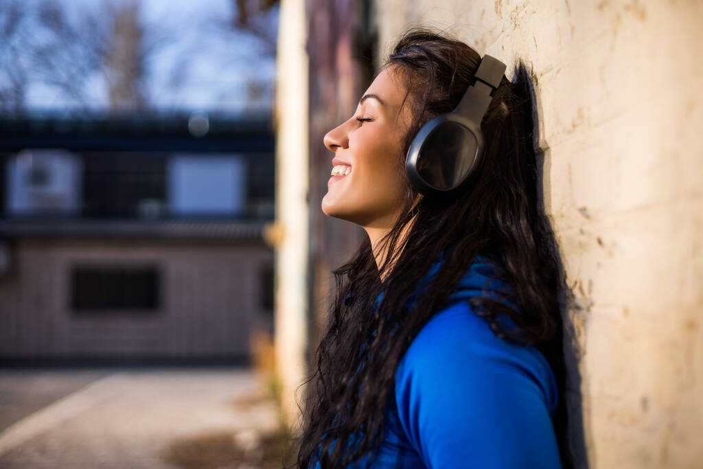 Kulaklıklı güzel, sportif bir kadın açık havada müzik dinlemekten hoşlanıyor.. - Fotoğraf, Görsel