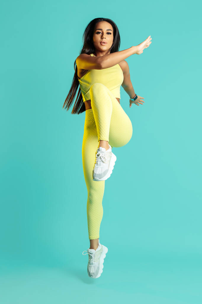 Athlétique jeune femme brune faisant des exercices fonctionnels sur fond bleu. Concept de puissance et de motivation. - Photo, image