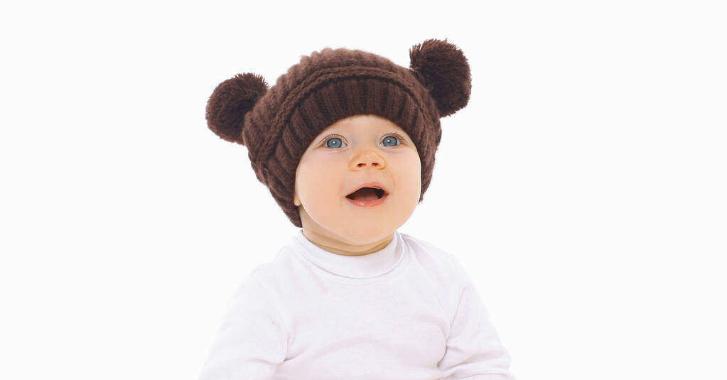 Πορτρέτο του χαριτωμένο μωρό σε καφέ καπέλο με αυτιά αρκούδα πάνω από ένα λευκό φόντο - Φωτογραφία, εικόνα