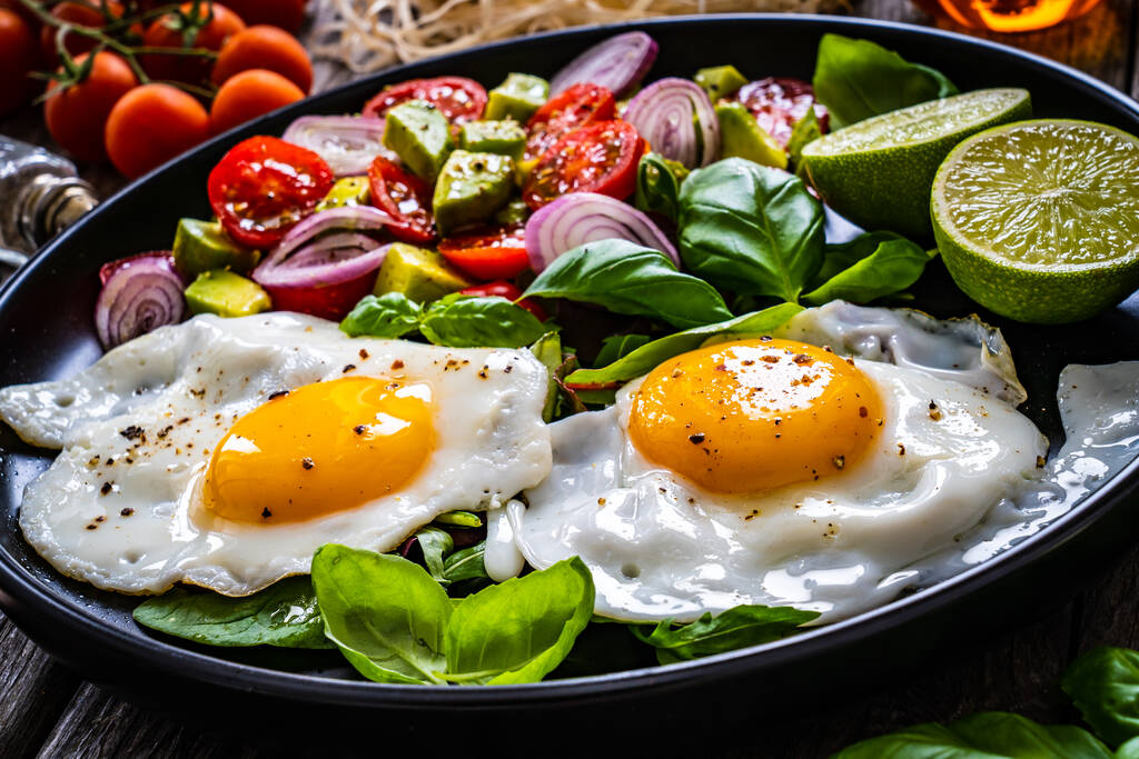 Avokado, kiraz domatesli yumurta, kızarmış ekmek ve ahşap masada kırmızı soğan.  - Fotoğraf, Görsel