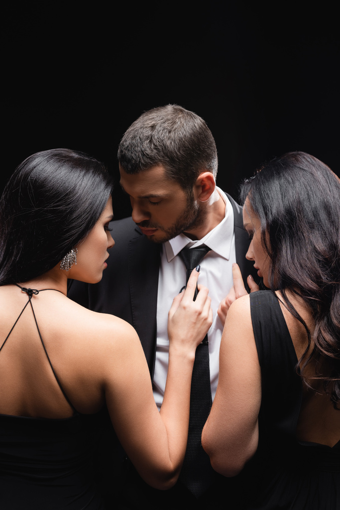 elegant, brunette women near young man in suit isolated on black - Photo, Image