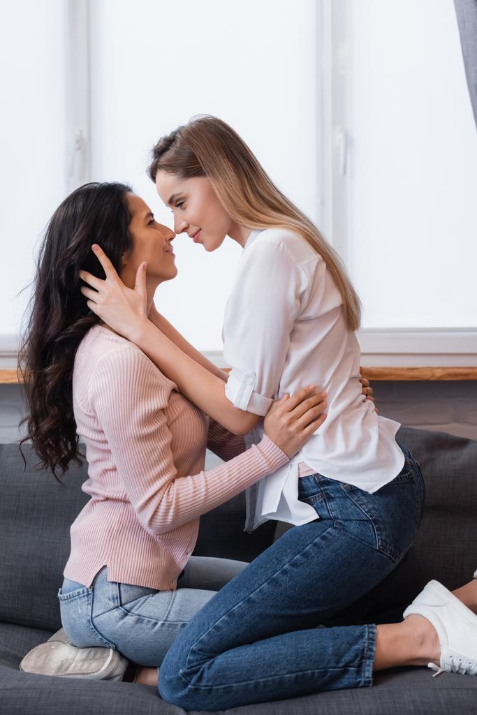 Seitenansicht glücklicher Lesben, die sich im Wohnzimmer umarmen - Foto, Bild
