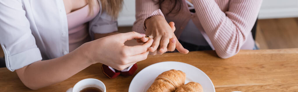cropped view of woman wearing wedding ring on finger of girlfriend at home, banner - Photo, image