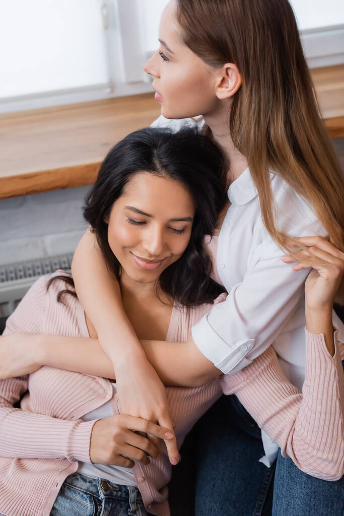 happy lesbian woman embracing girlfriend in living room - Zdjęcie, obraz