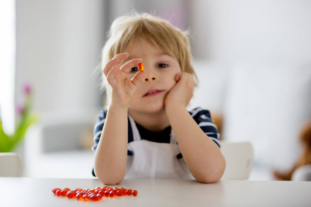 Criança pequena bonito, menino da criança, comendo alfa omega 3 criança suplementar pílulas vitamínicas em casa para melhor imunidade - Foto, Imagem
