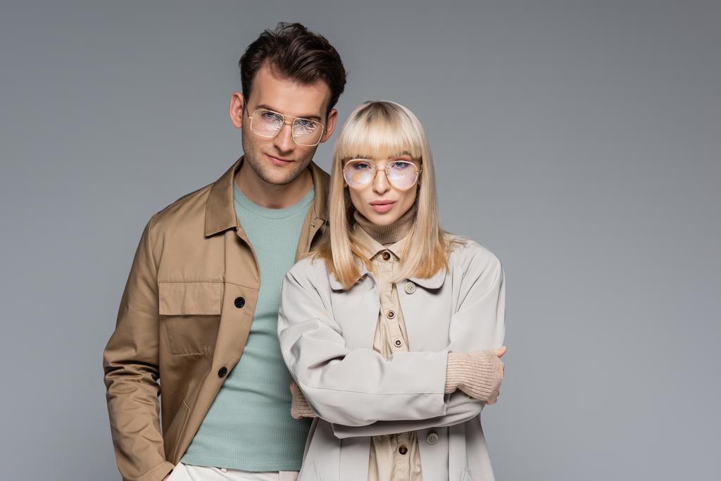 stylish couple in glasses posing and looking at camera isolated on grey - Photo, Image