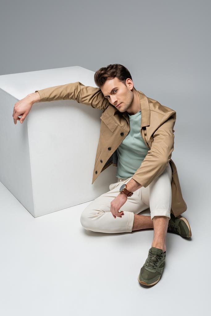 повна довжина модного чоловіка позує, спираючись на білий куб на сірий
 - Фото, зображення