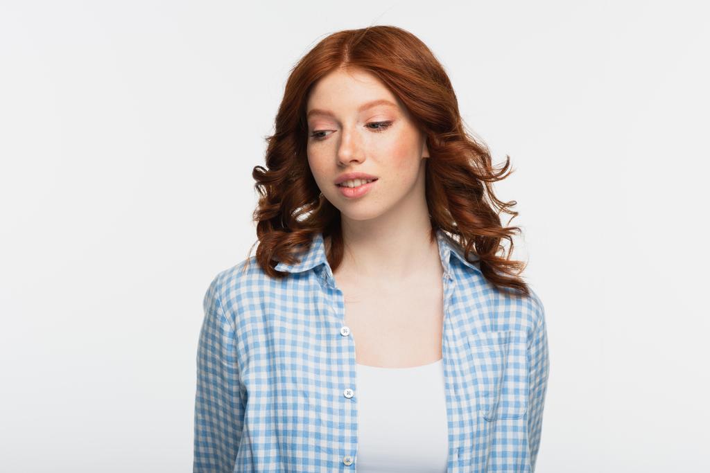 mujer joven soñadora con camisa a cuadros azul mirando hacia otro lado aislado en blanco - Foto, Imagen