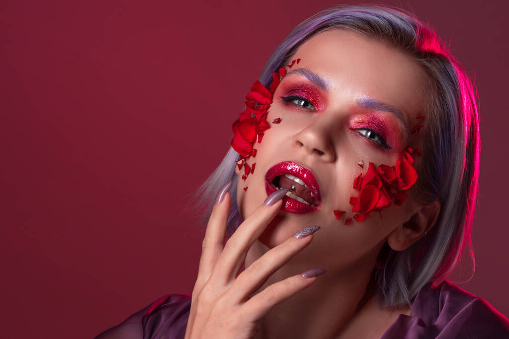 Aspecto vampiro glamuroso con sombra de ojos de color rosa brillante y pétalos de flores en la piel - Foto, Imagen