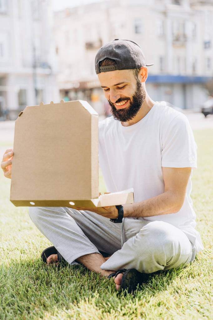 Homme barbu élégant avec une boîte de pizza en carton, placer sous votre texte ou logo - Photo, image