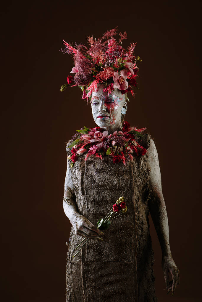 Dziewczyna rozmazana gliną. Model ma nakrycie głowy zrobione z kwiatów.. - Zdjęcie, obraz